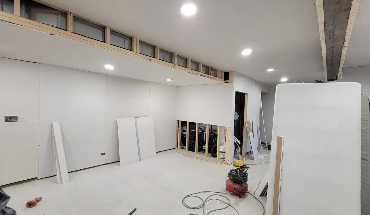 A basement undergoing a finishing process, with walls framed and drywall installed—complete your basement transformation today.