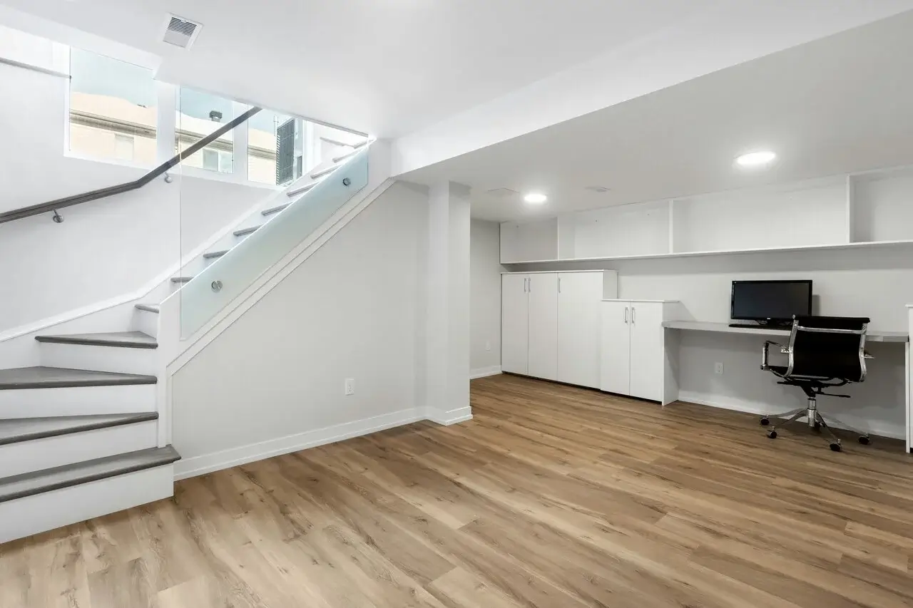 Bright and modern finished basement with light wood flooring. Thinking of upgrading your basement flooring? Contact us today for expert advice!