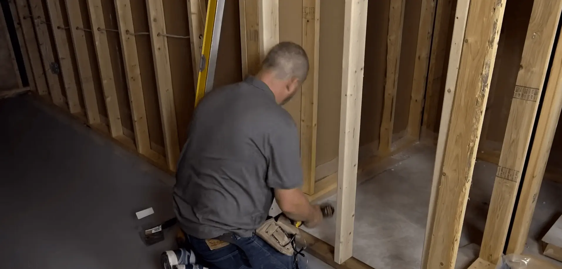 A contractor framing a basement wall with precision tools. Start building your dream space today!