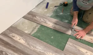 A person installing vinyl flooring in a basement, using a square tool to ensure precision cuts. Get expert help to finish your basement faster and more efficiently today!