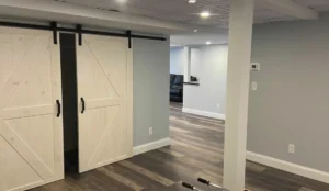 Completed basement renovation with sliding barn doors and modern flooring. Transform your basement into a stunning, functional space with Newton Basement Finishing's expert services!