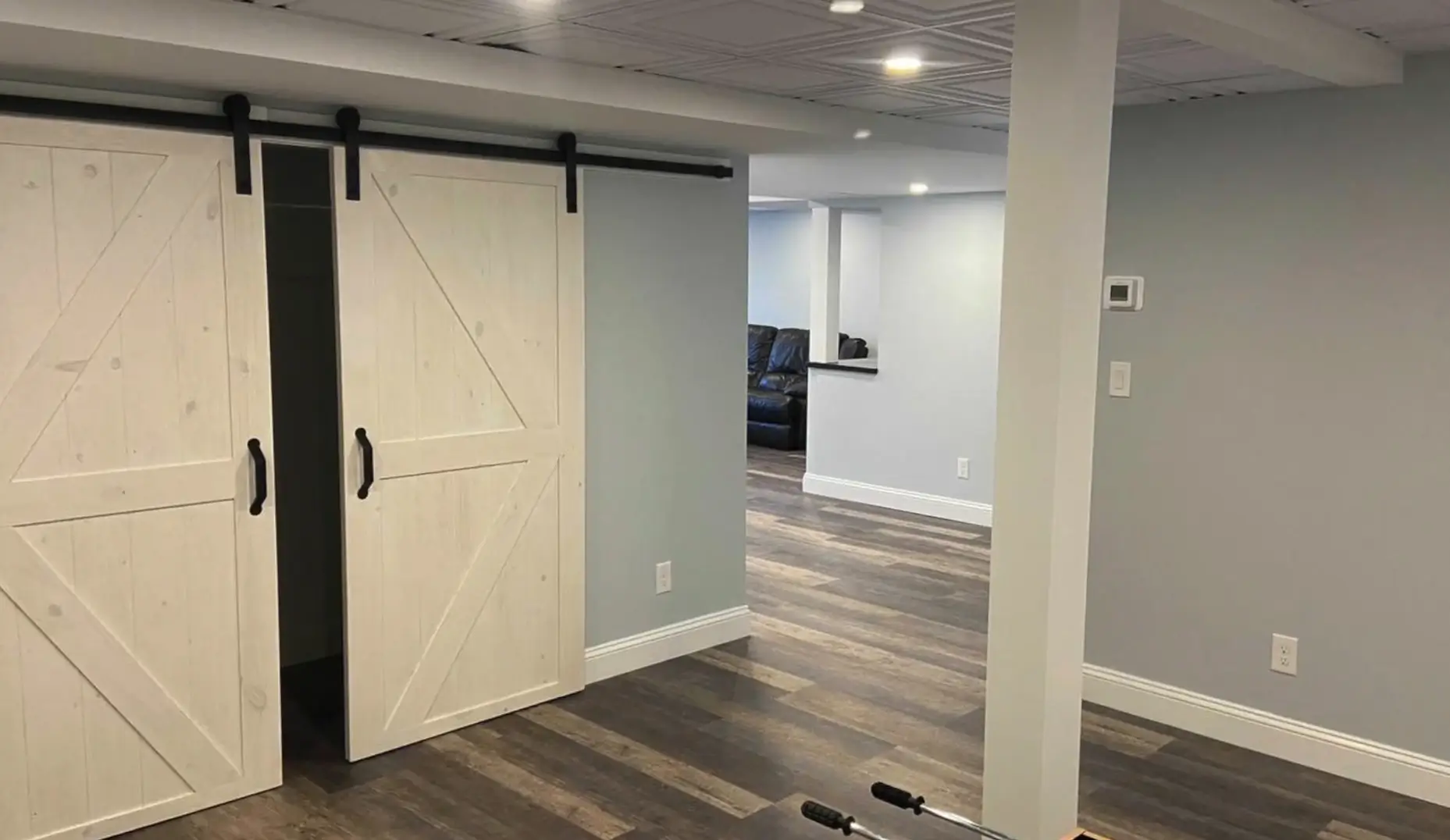 Completed basement renovation with sliding barn doors and modern flooring. Transform your basement into a stunning, functional space with Newton Basement Finishing's expert services!